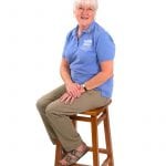 an image of a woman in a blue shirt sitting on a stool