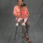 an image of a woman holding her 1 year old baby girl while sitting on a stool together