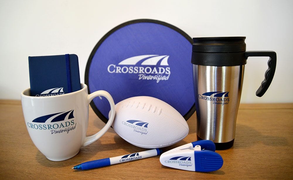 crossroads-swag Crossroads Diversified swag, including a mug, foam football, magnet clip, pen, coffee thermos, and notebook