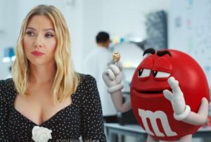 The red M&M talking to a blonde haired woman with