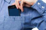 a truncated photo of a person putting a cell phone into their shirt pocket