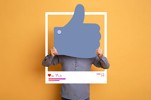 An image of a person holding up a very large blue thumbs up cutout in front of their face.