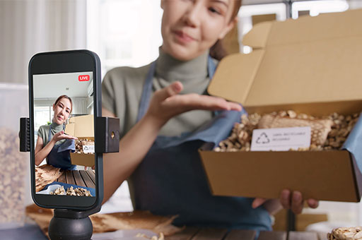 A person showing off a box and someone else recording it with their phone