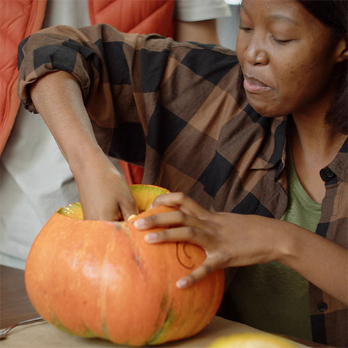 a woman carving out a pumpkin